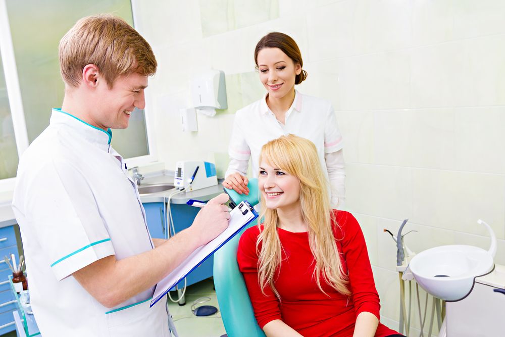Dentist in dental office talking with female patient